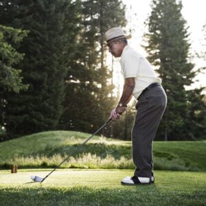 senior golfer teeing off during a round of golf H3R59SZ