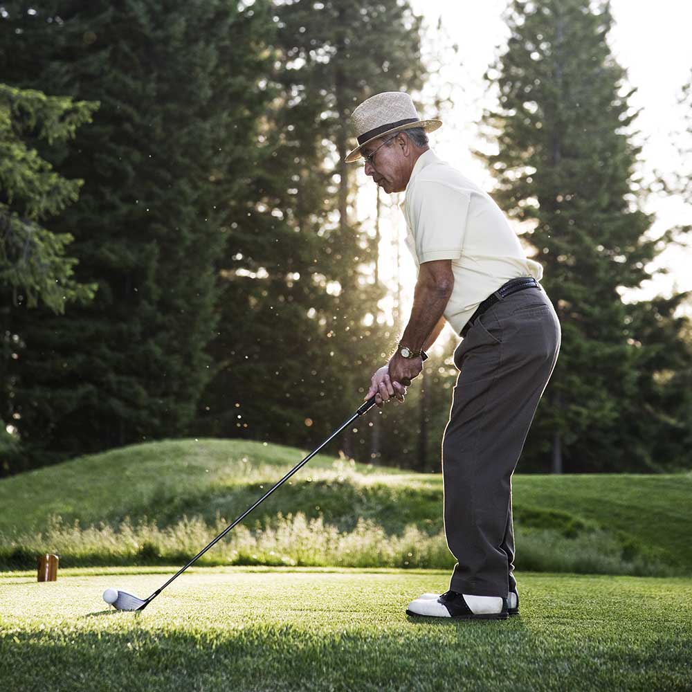 senior golfer teeing off during a round of golf H3R59SZ