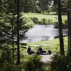 two golf carts parked on a golf course YFVFGDU